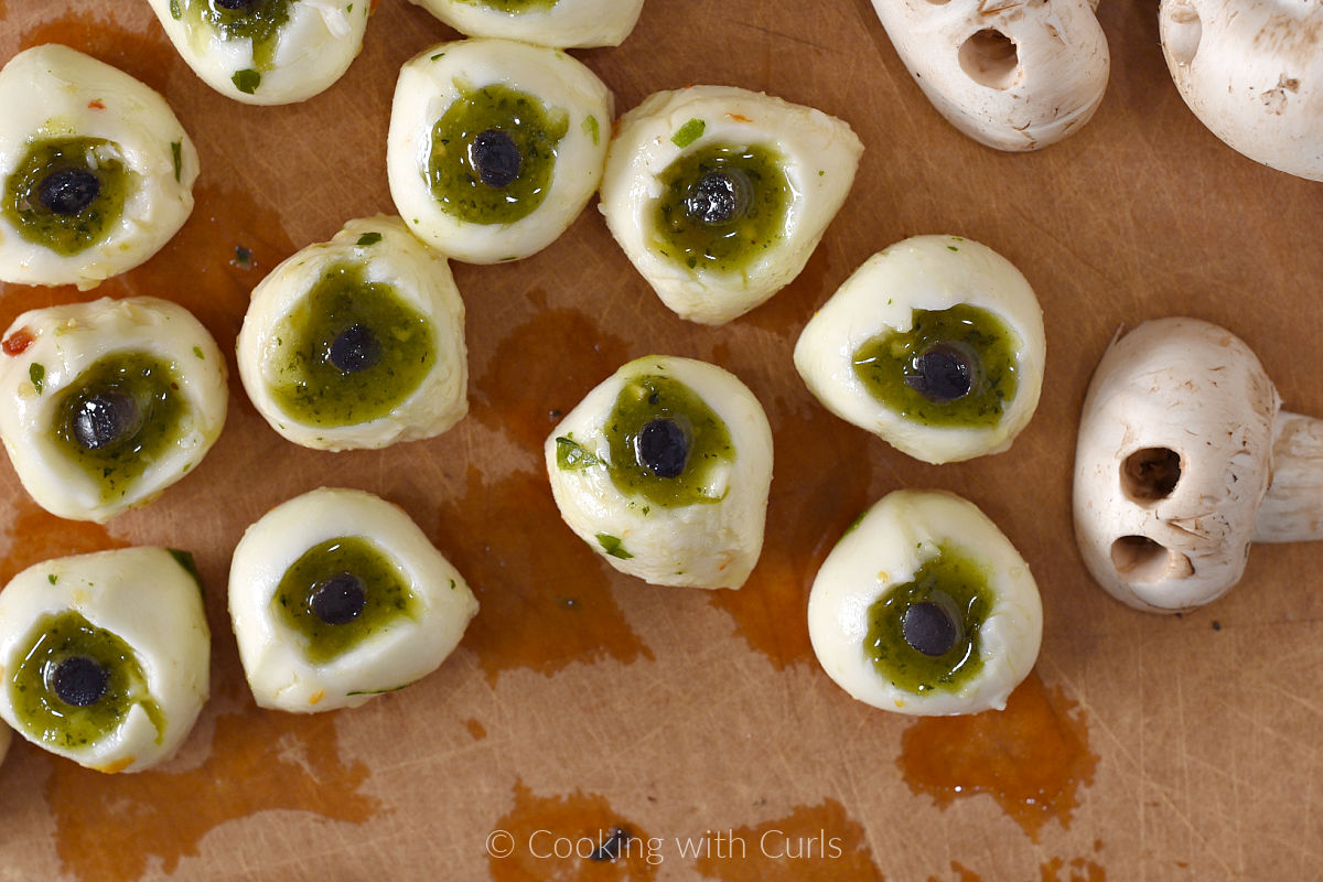 Mozzarella balls with pesto and black olive eyes.