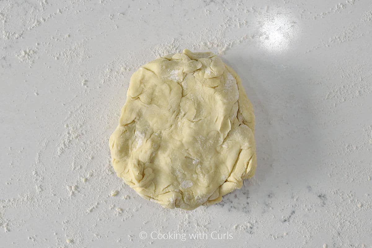 Ball of puff pastry dough on a floured work surface.