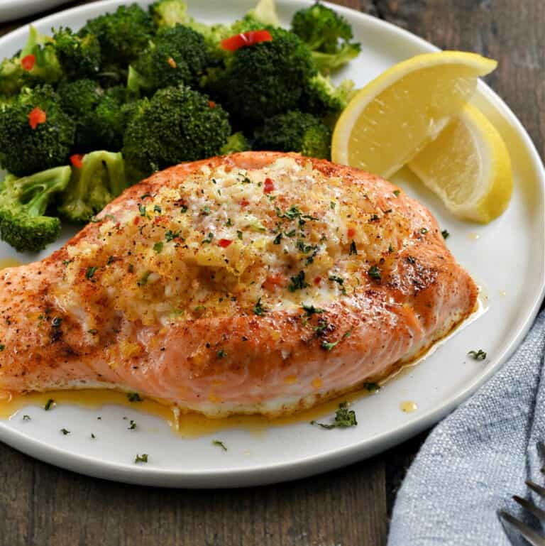 Crab stuffed salmon with steamed broccoli and lemon wedges.