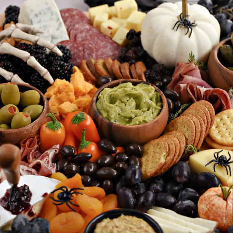 Halloween themed charcuterie board with meats, cheeses, crackers, and fruits.