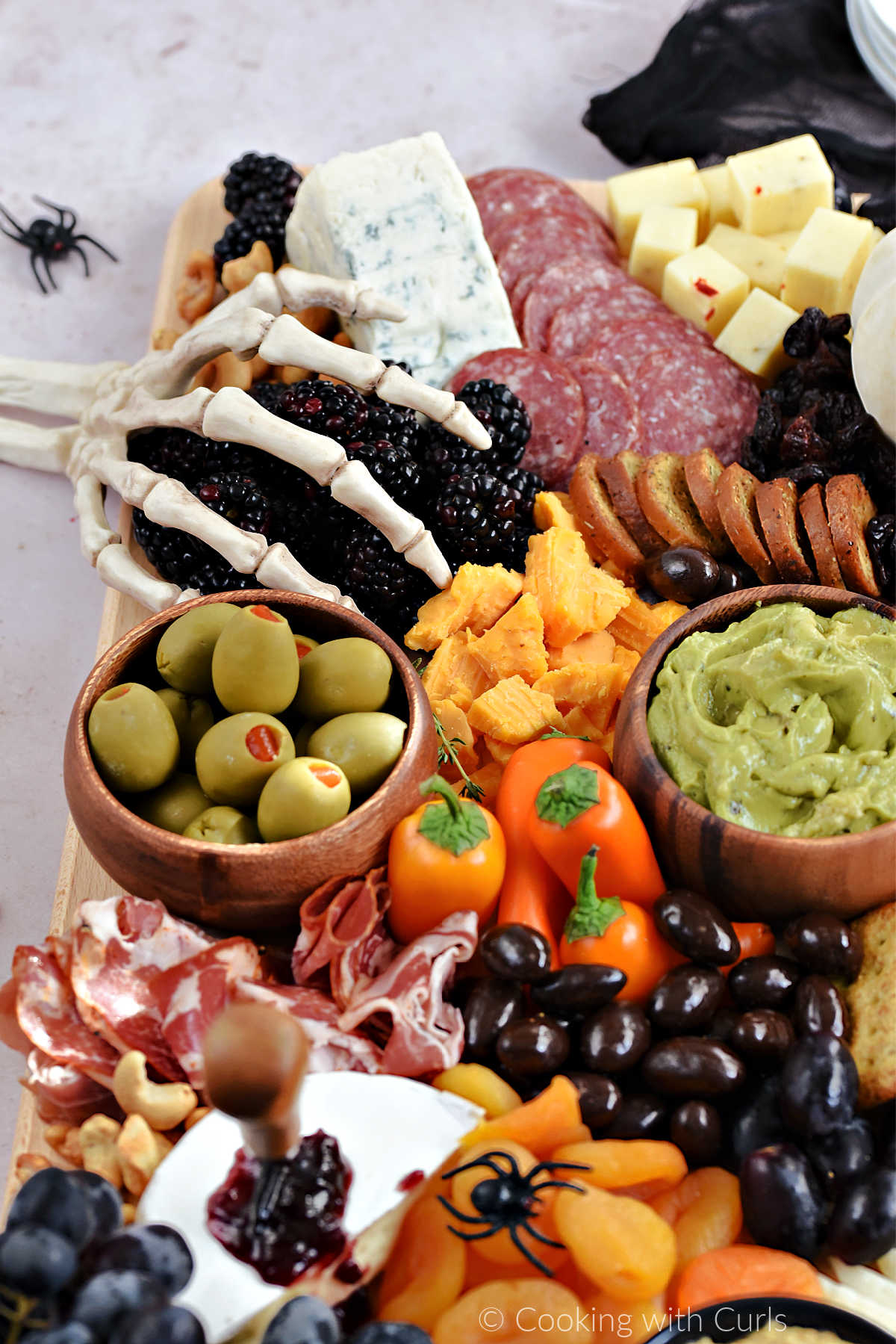 Meats, cheeses, fruits, and nuts on a wood board.
