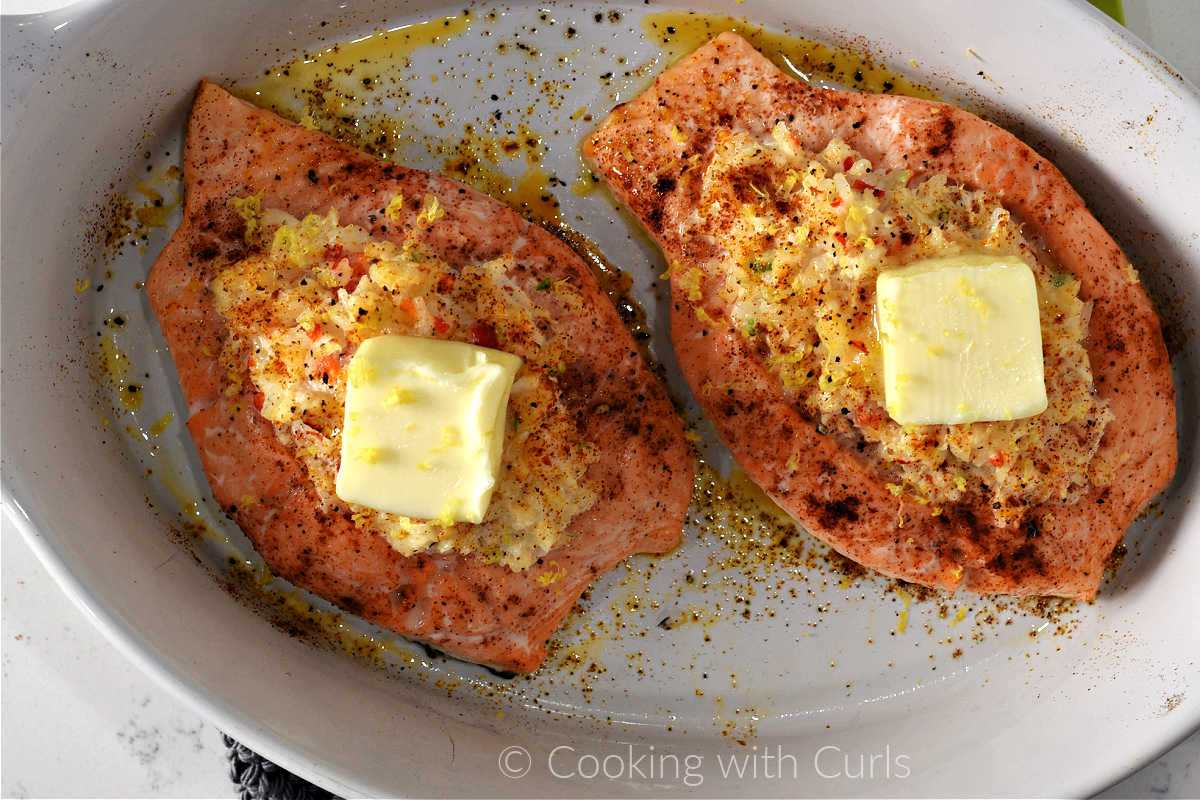 Two baked crab stuffed salmon fillets with a pat of butter on top.