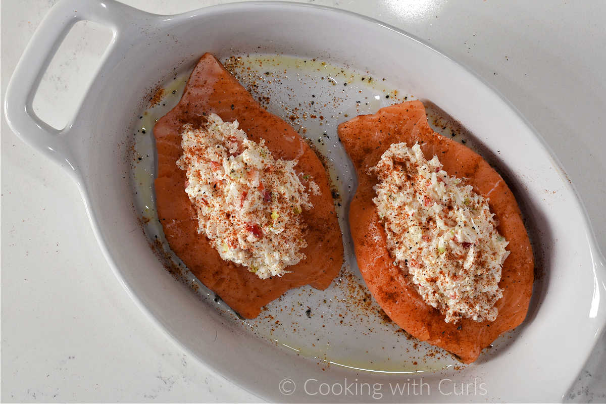 Two fresh salmon fillets stuffed with crab filling in a baking dish.