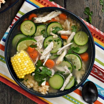 Chicken, sliced zucchini, carrots, and corn on the cob in a bowl.
