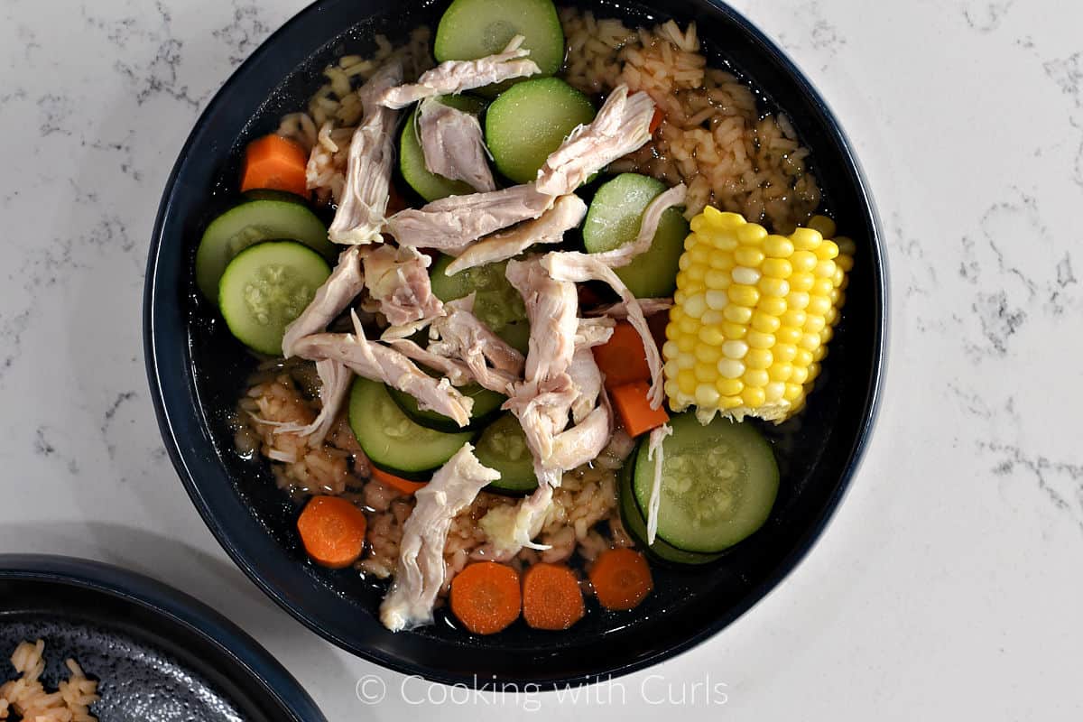 Rice, vegetables, and shredded chicken in a serving bowl.