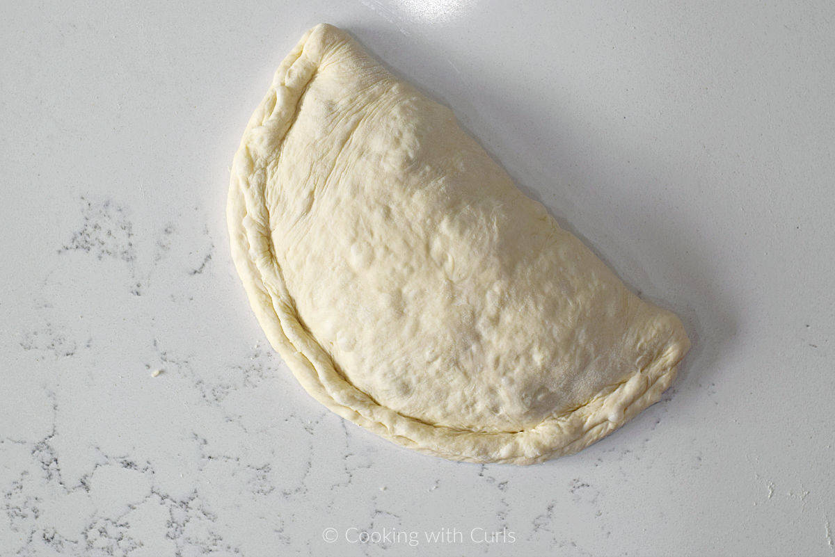 A raw calzone on a marble slab.