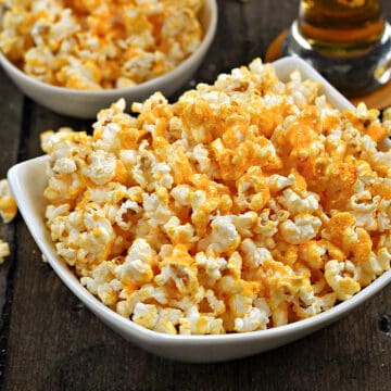 Two bowls of overflowing cheddar cheese popcorn.