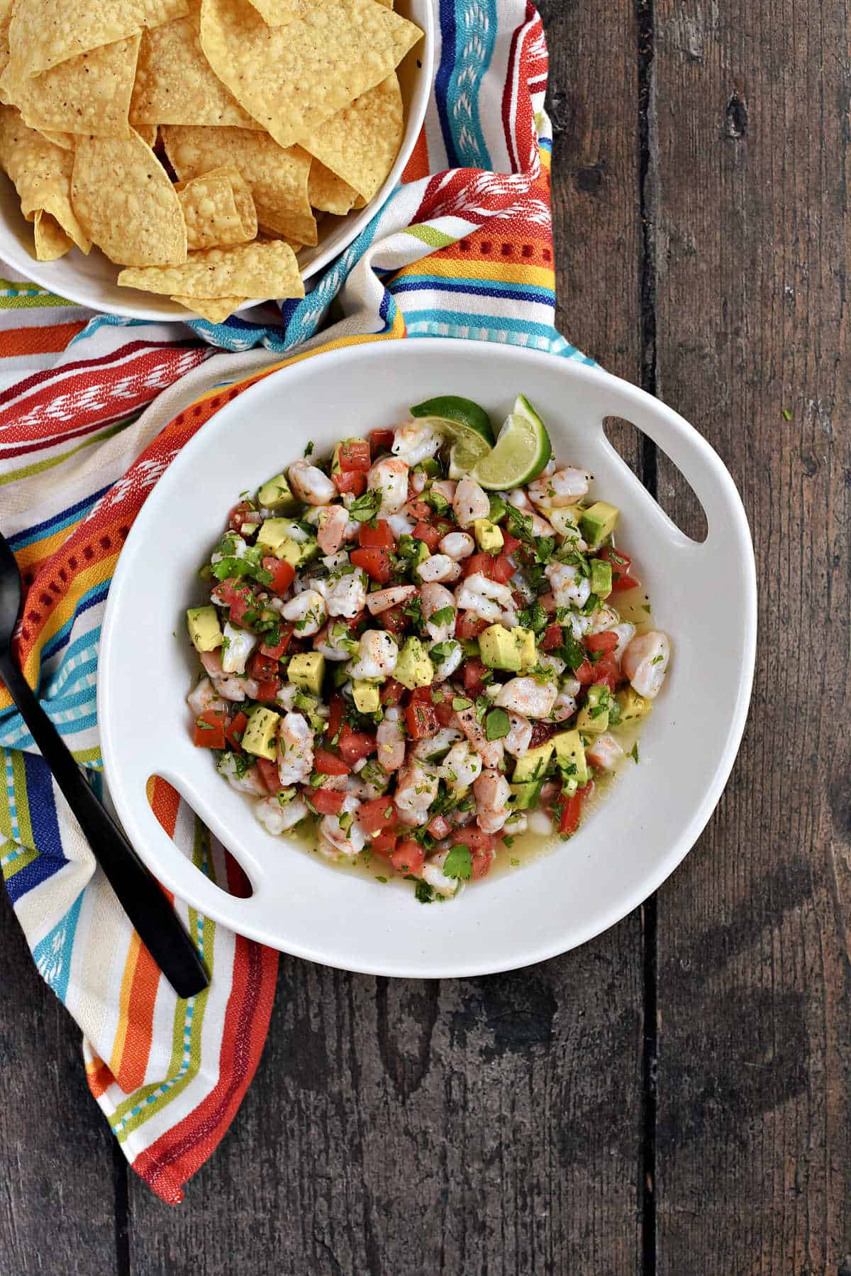 A large serving bowl with shrimp ceviche mixed with tomato and avocado.
