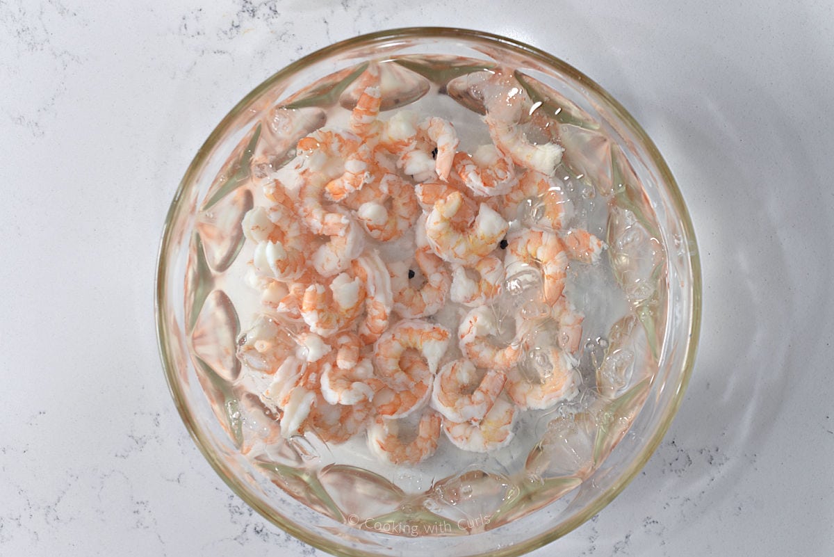 Cooked shrimp and ice water in a large bowl.