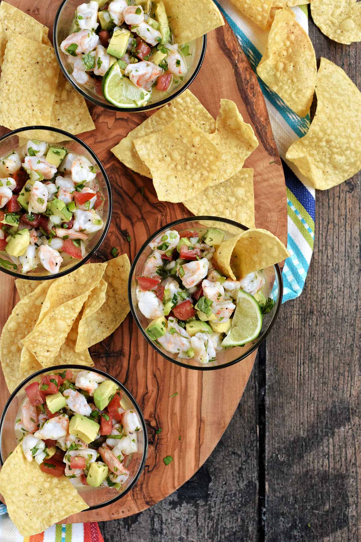 Mexican shrimp ceviche in four small glass bowls surrounded by tortilla chips.