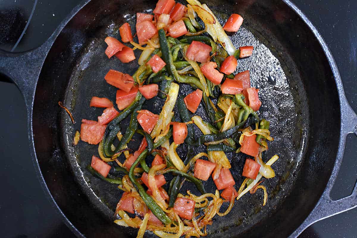 Poblano pepper strips, sliced onions and diced tomato in skillet.