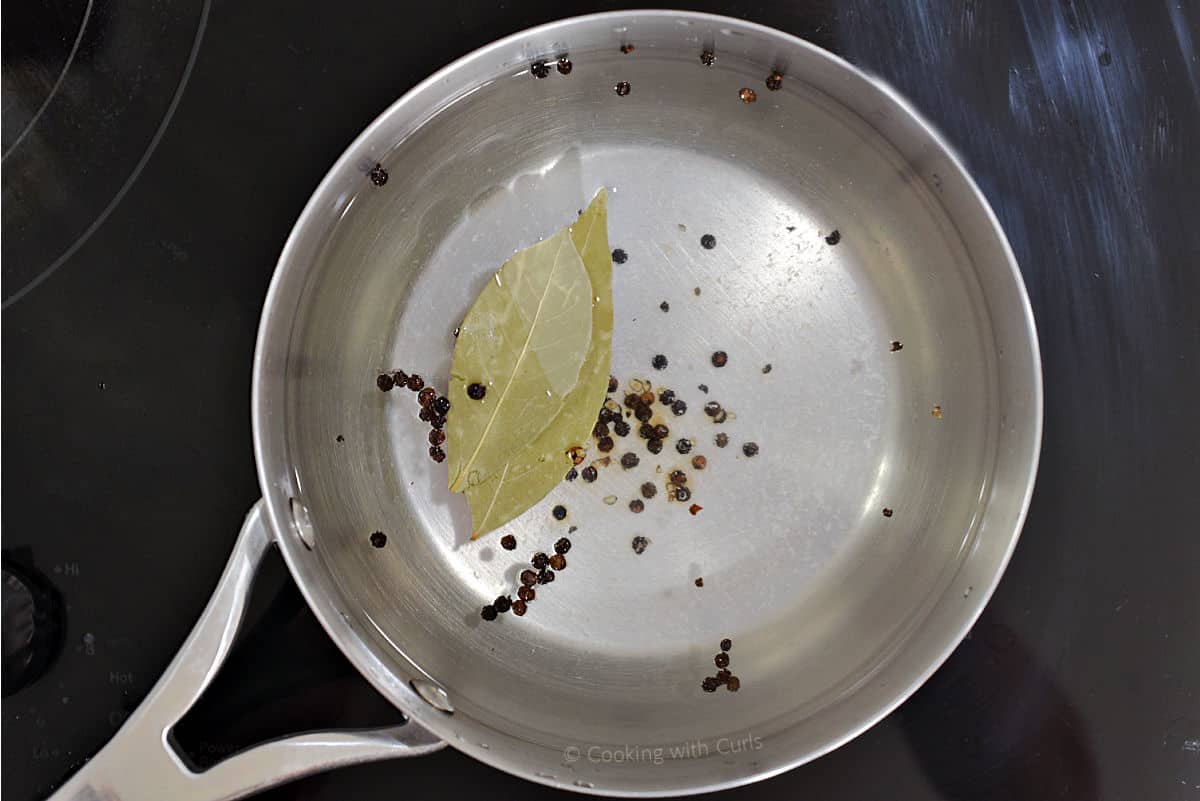 Saucepan with water, peppercorns, bay leaves, and lemon juice.
