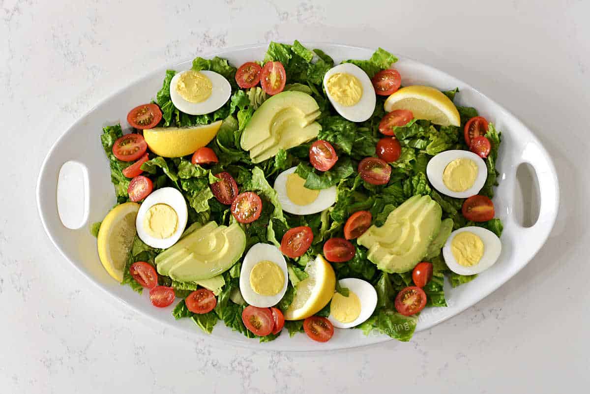 Oval platter with sliced avocado, cherry tomatoes, and egg halves.