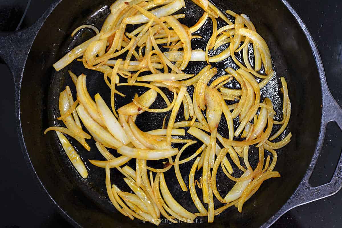 Thin onion slices cooking in a cast iron skillet.