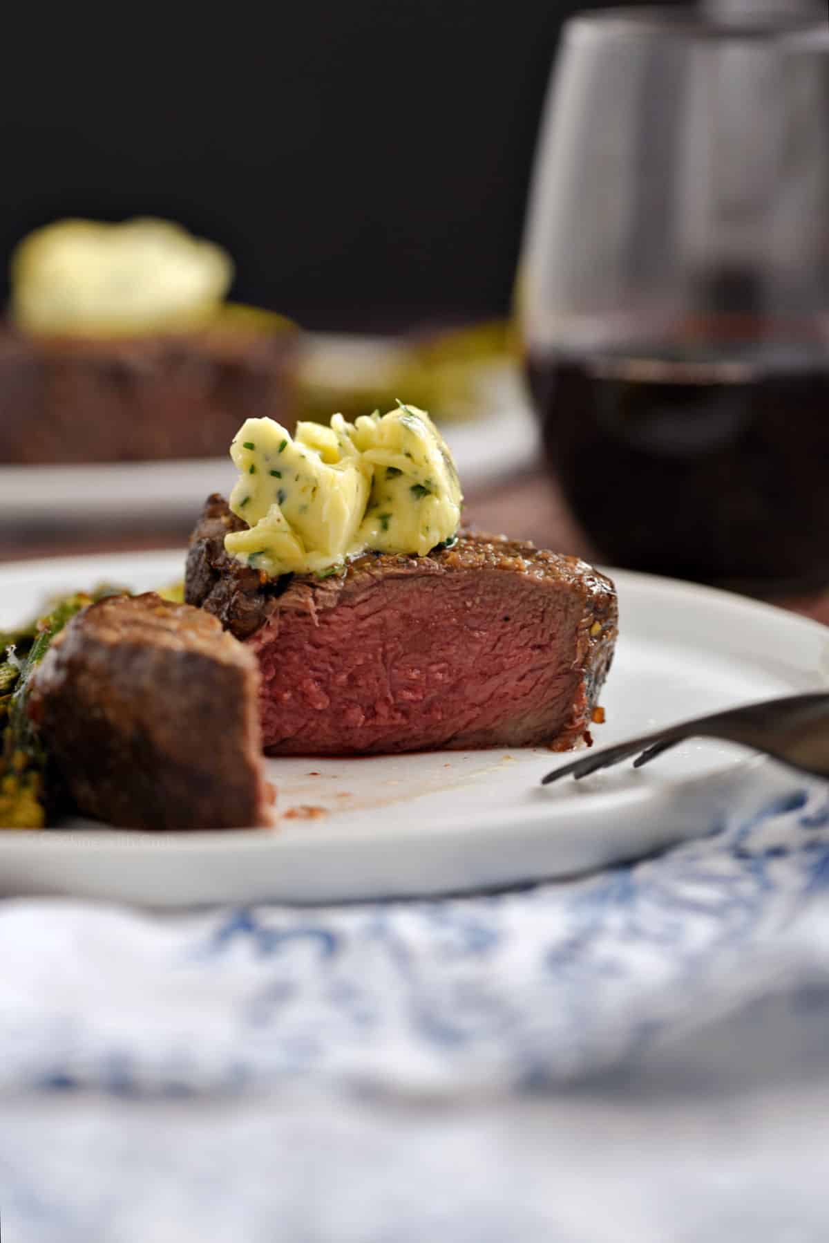A steak topped with herb butter cut open on a plate.