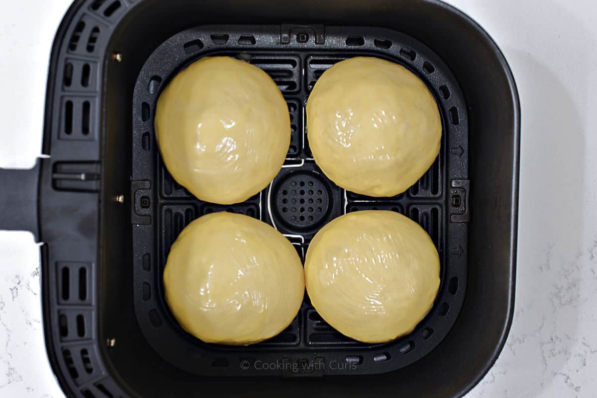 Four buttered dough balls in air fryer basket.