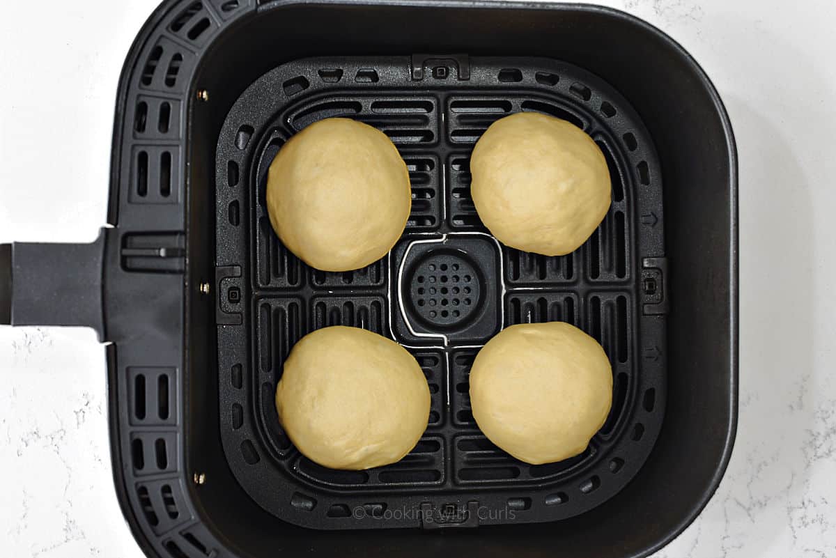 Four dough balls in air fryer basket.