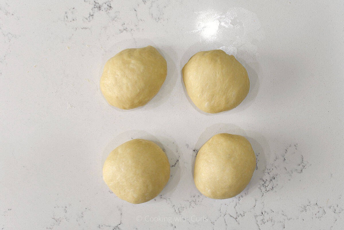 Four dough balls on work surface.