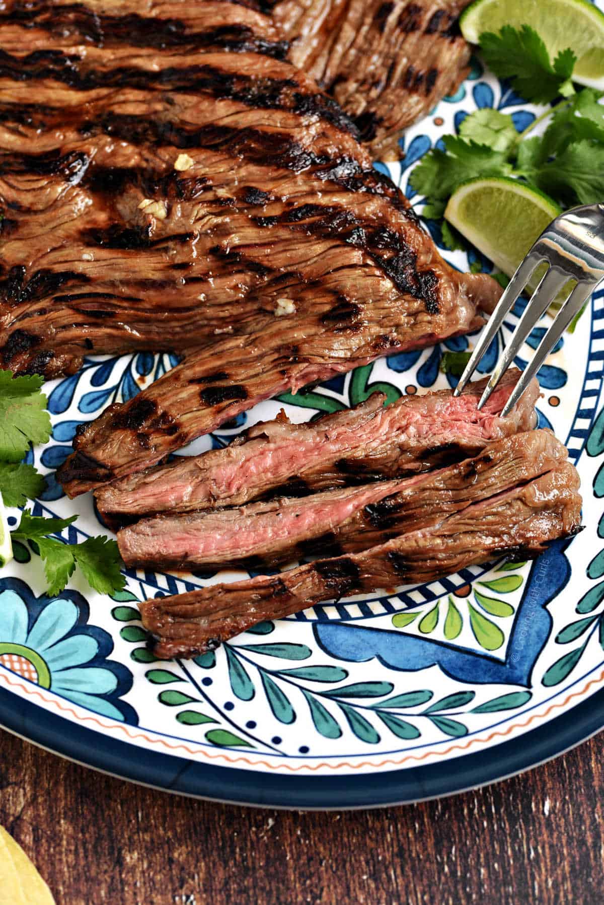 Sliced carne asada steak on a colorful platter.