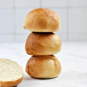 Three stacked hamburger buns with one sliced in half on the side.