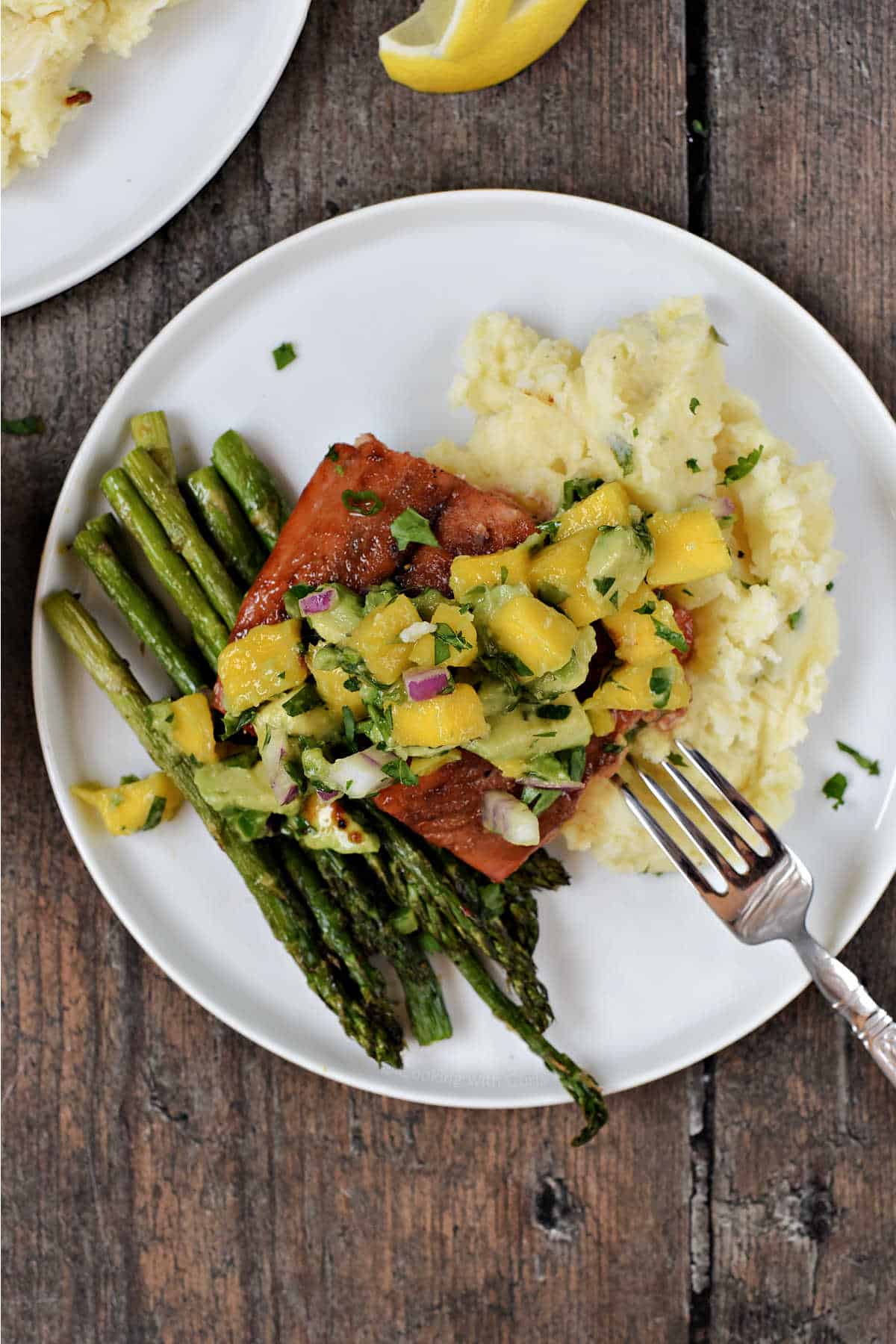 Salmon topped with mango avocado salsa on a bed of mashed potatoes and asparagus spears.