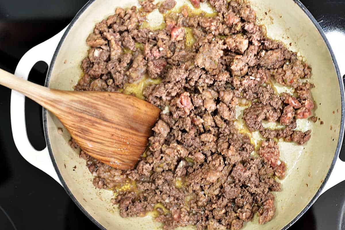 Ground beef and Italian sausage cooking in a skillet.