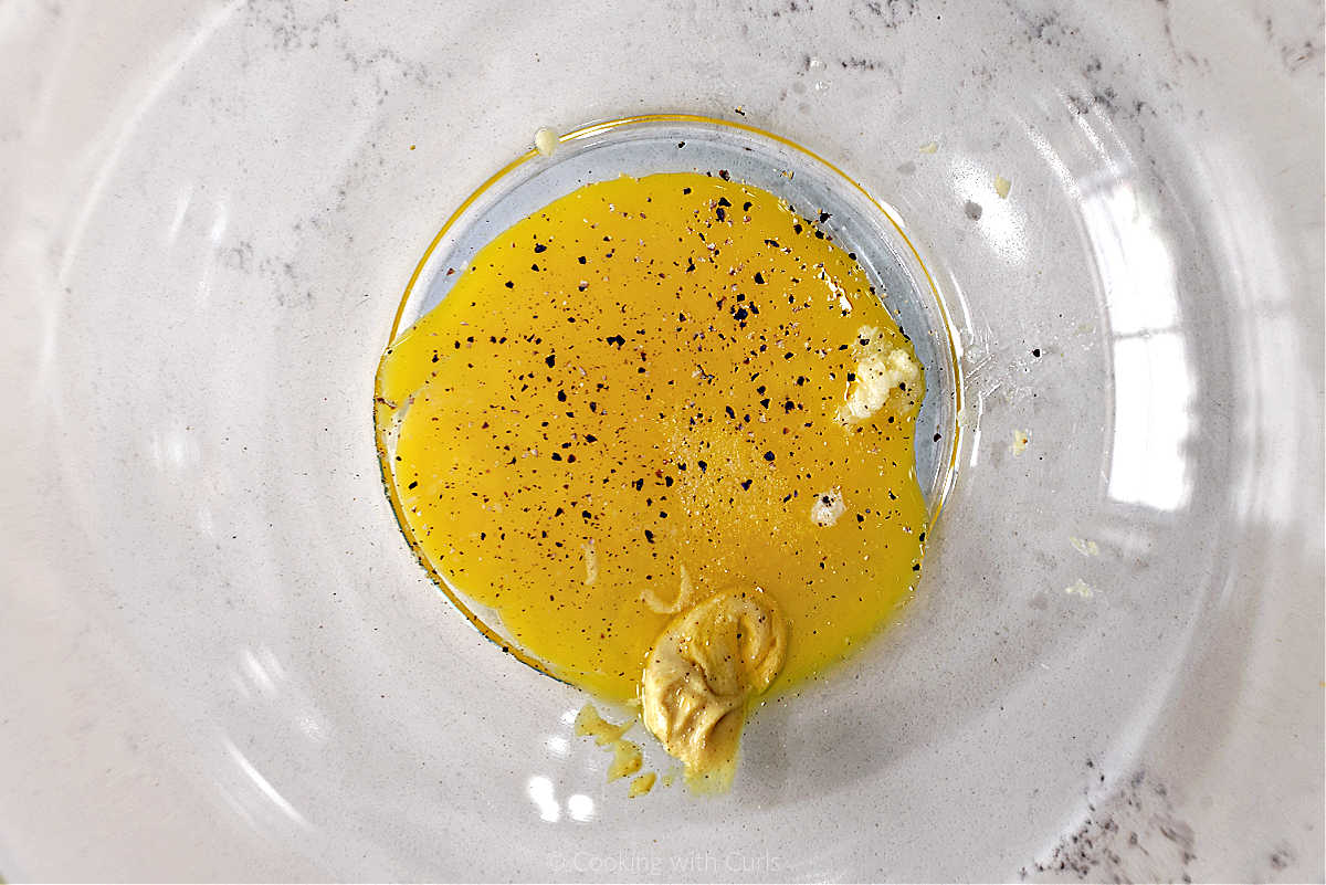 Egg yolk, mustard, and garlic in a mixing bowl.