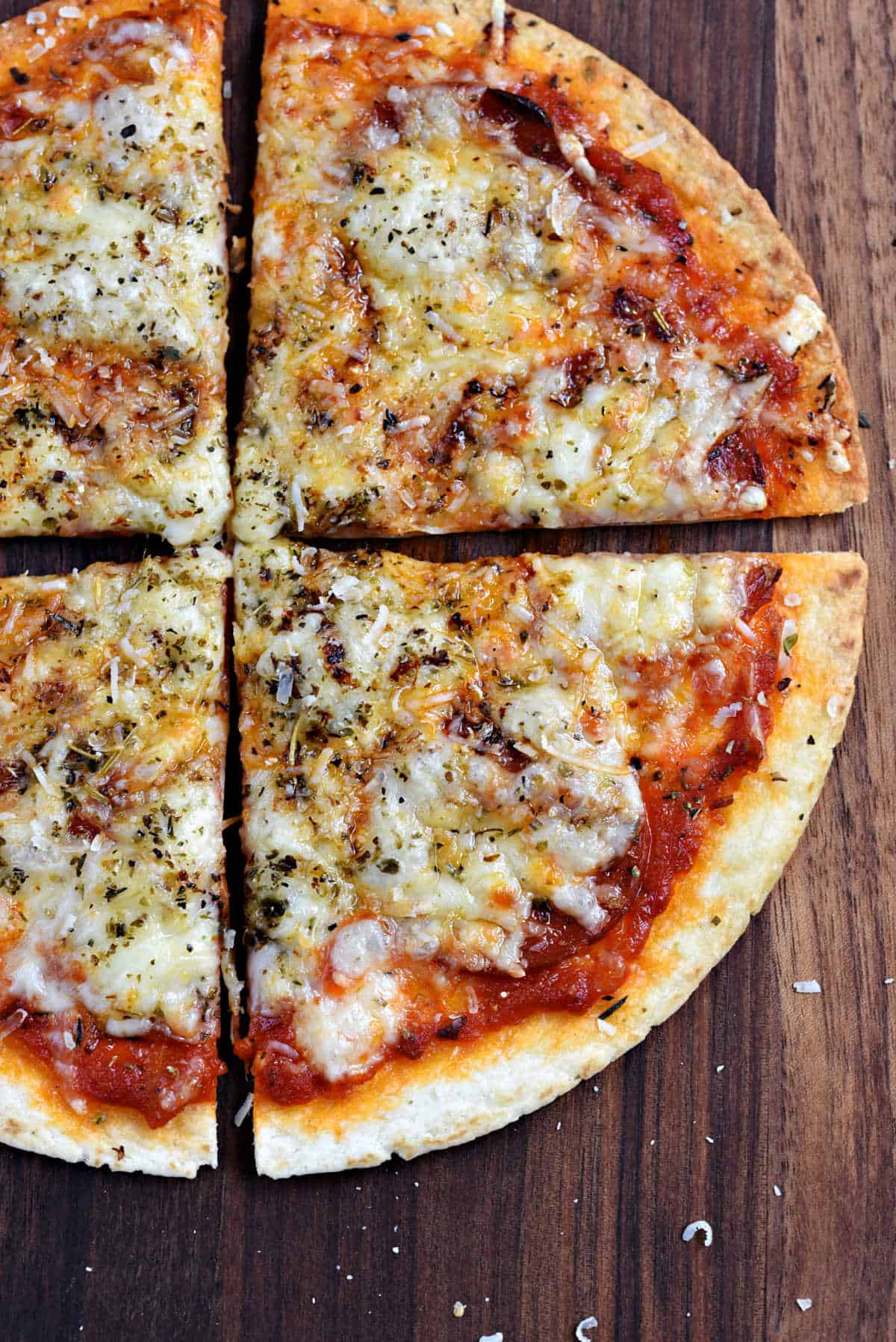 Air fryer tortilla pepperoni pizza cut into quarters on a wooden board.