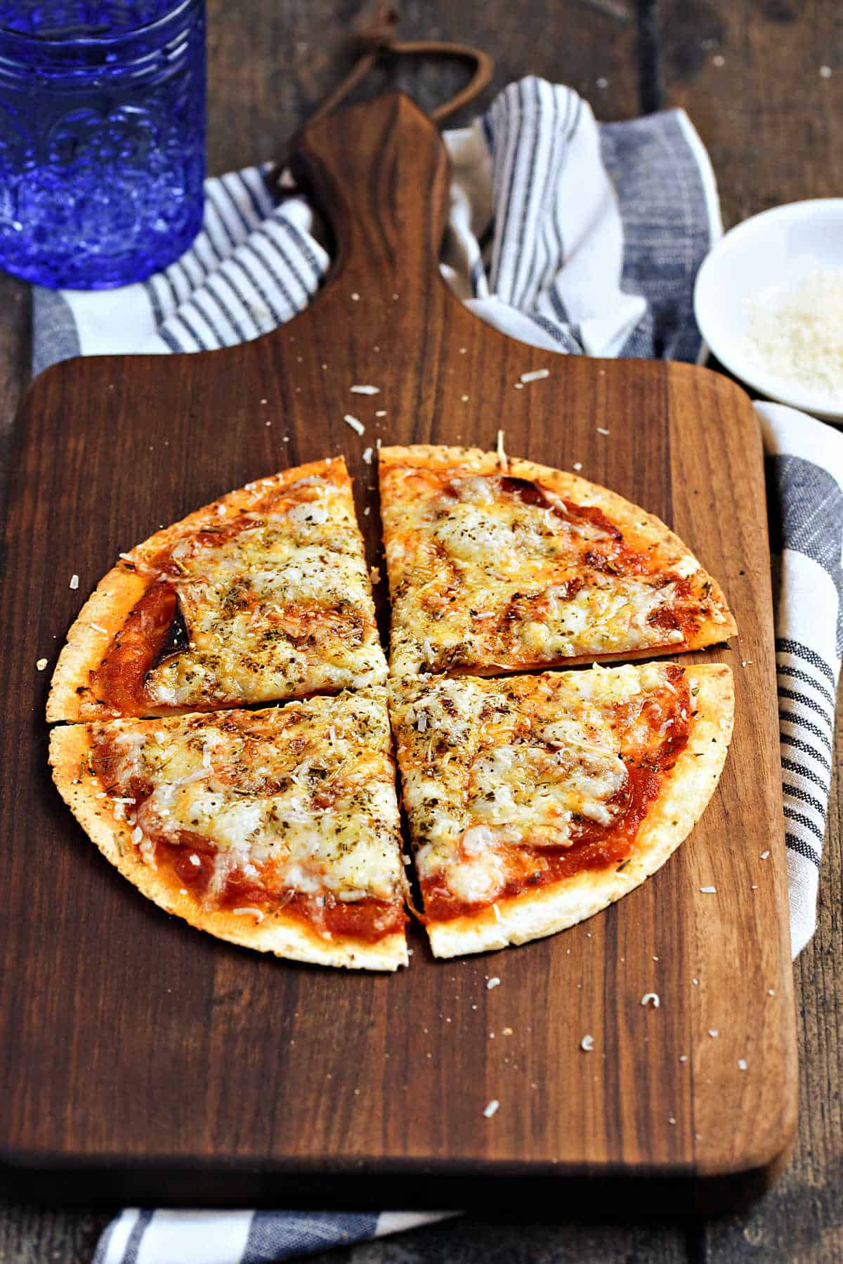 Air fryer tortilla pizza with pepperoni on a wooden cutting board.