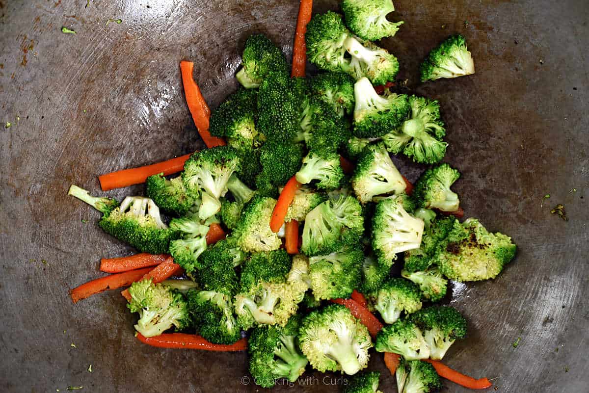 Broccoli florets and red pepper strips in a wok.