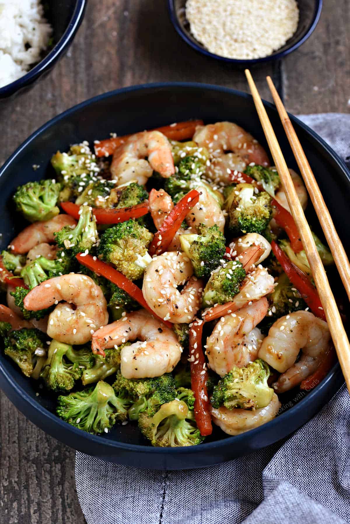 Shrimp and vegetable stir fry in a bowl with chop sticks on the edge.