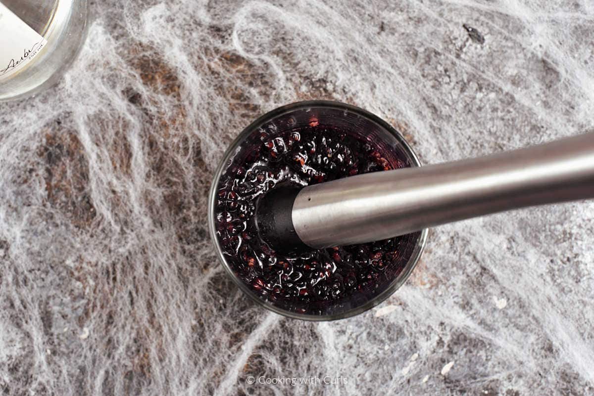 Blackberries muddled in a metal cocktail shaker.