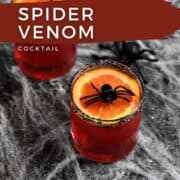 Red drink in short glasses topped with orange slice and plastic spider sitting on a spider web surrounded by small plastic spiders with title graphic across the top.