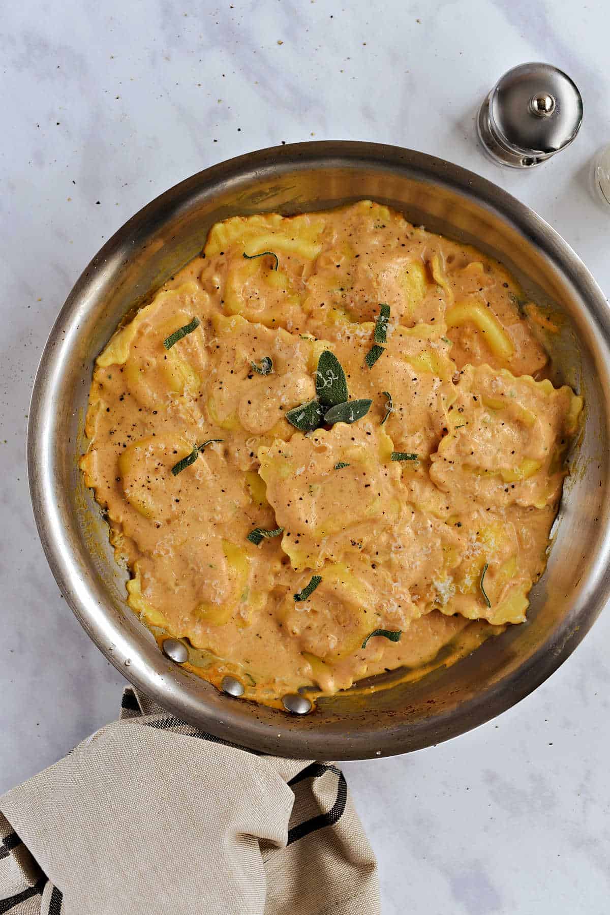 A skillet with ravioli in a creamy pumpkin sauce.