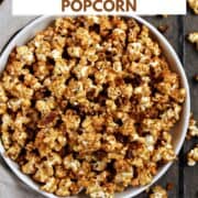 A bowl of caramel popcorn with candied pecans surrounded by scattered popcorn and title graphic across the top.