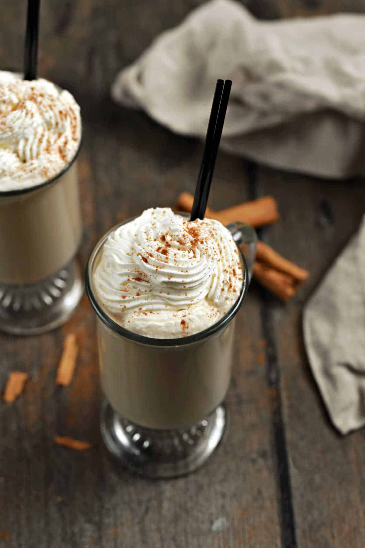 Two glass mugs with coffee drink topped with whipped cream and cinnamon.