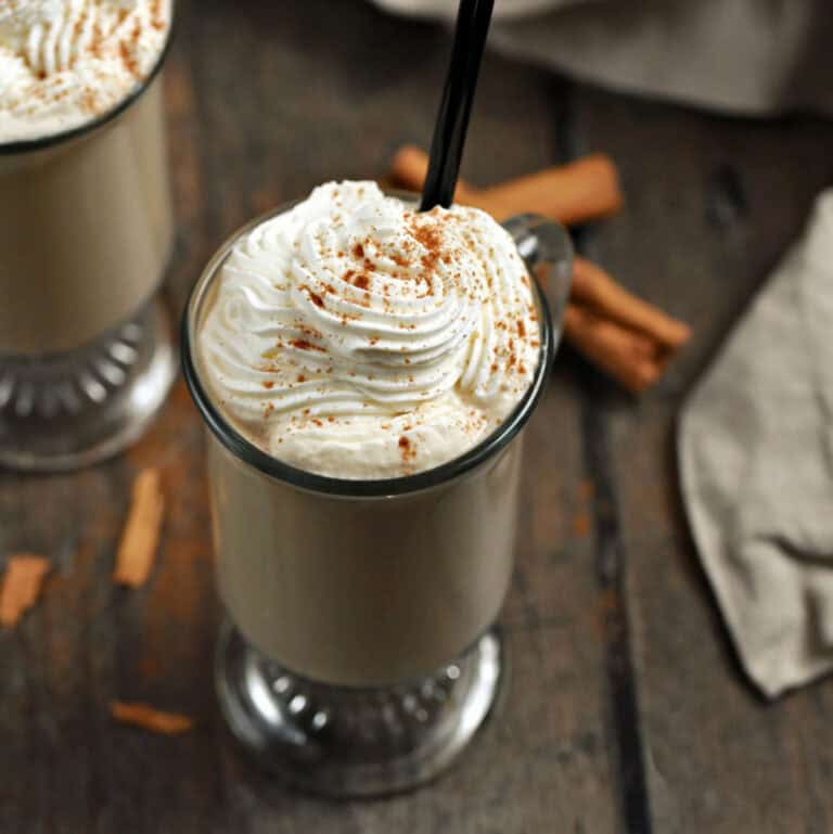 Two glass mugs with coffee drink topped with whipped cream and cinnamon.