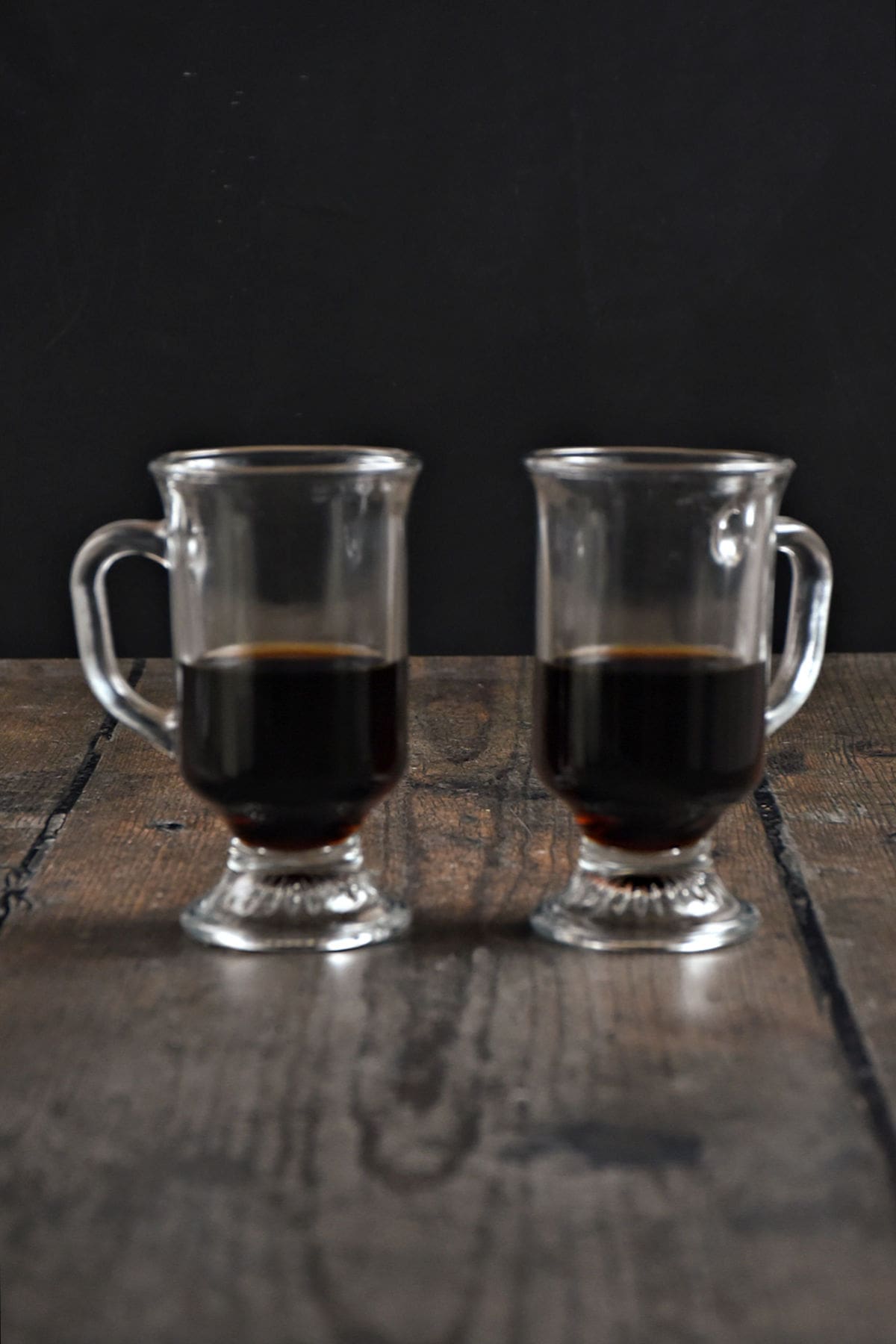 Two half filled glass mugs with coffee and liqueurs.