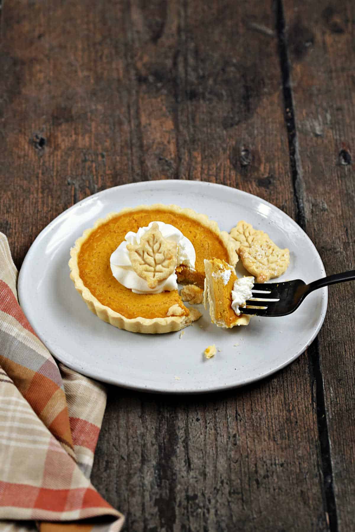 Mini pumpkin pie with bite of pie on a fork.