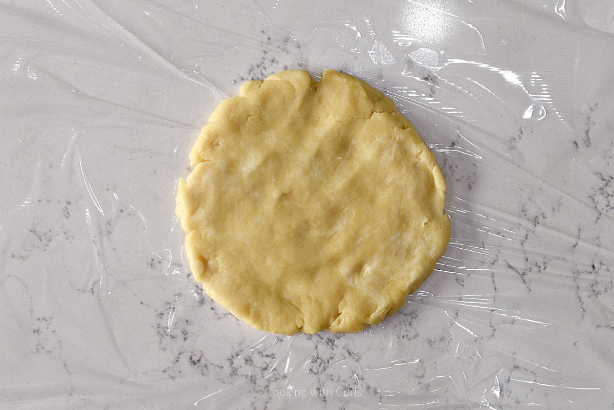 Pie crust disk on plastic wrap.