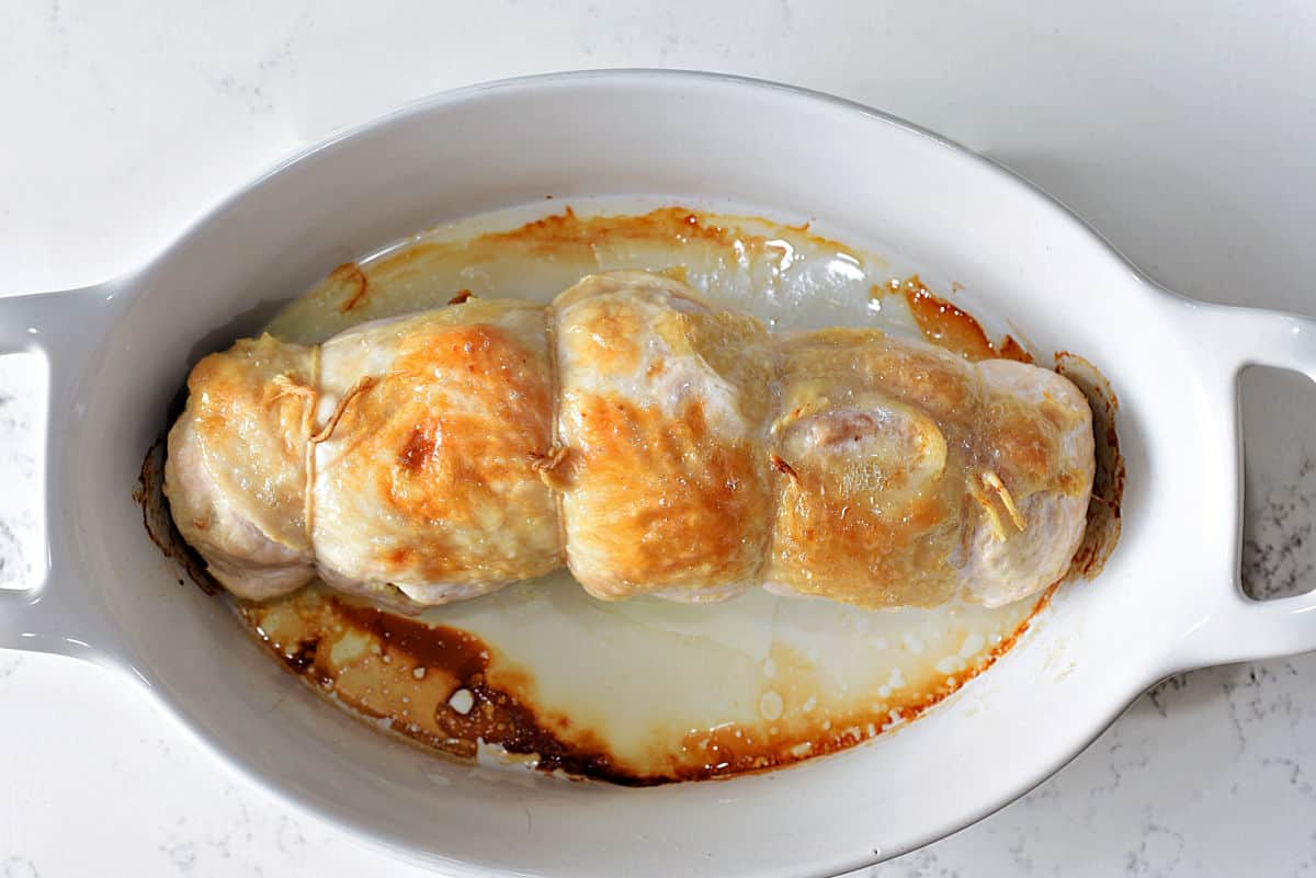 Roasted, stuffed turkey breast in baking dish.