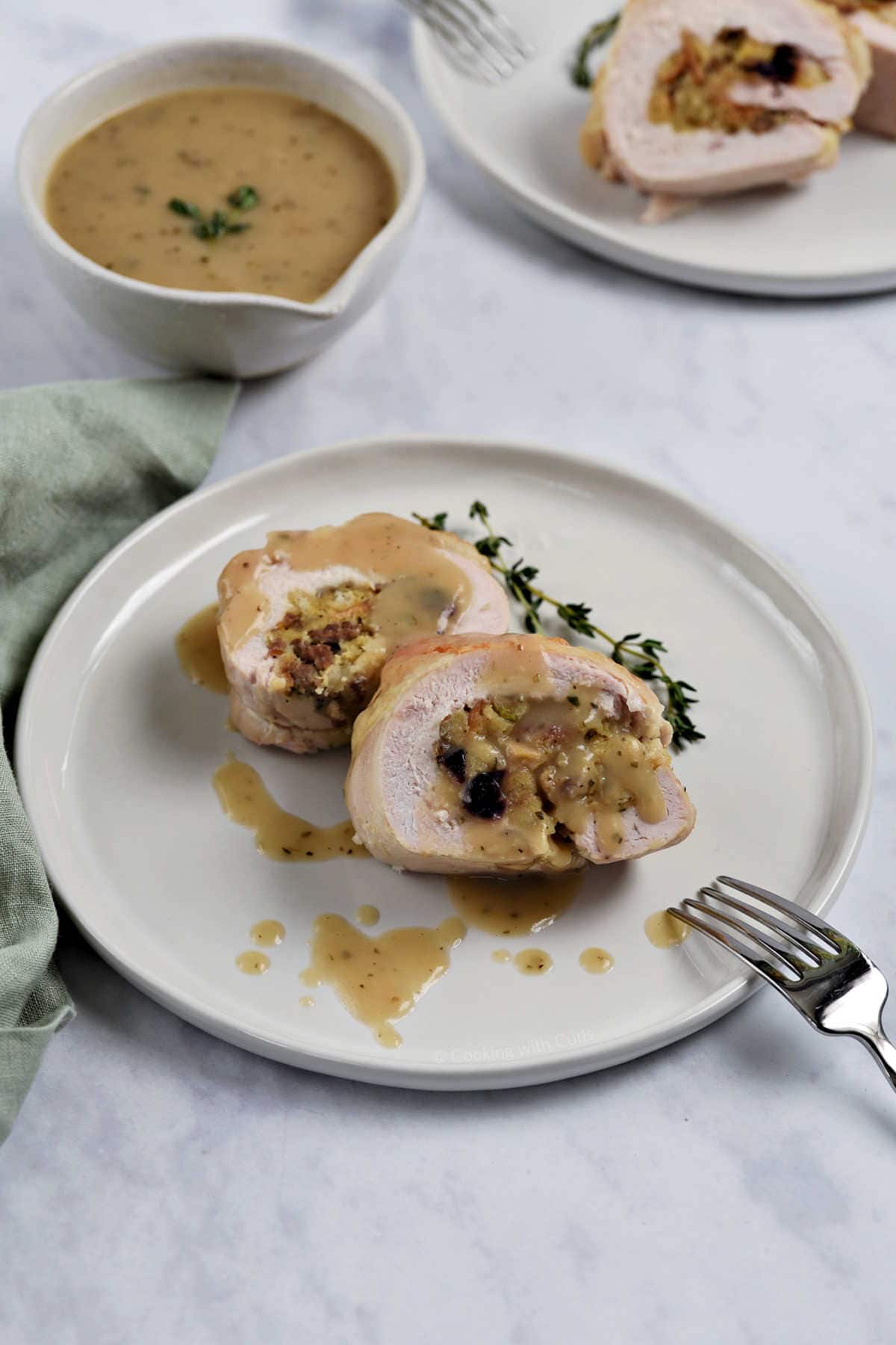 Two slices of stuffed turkey breast topped with gravy.