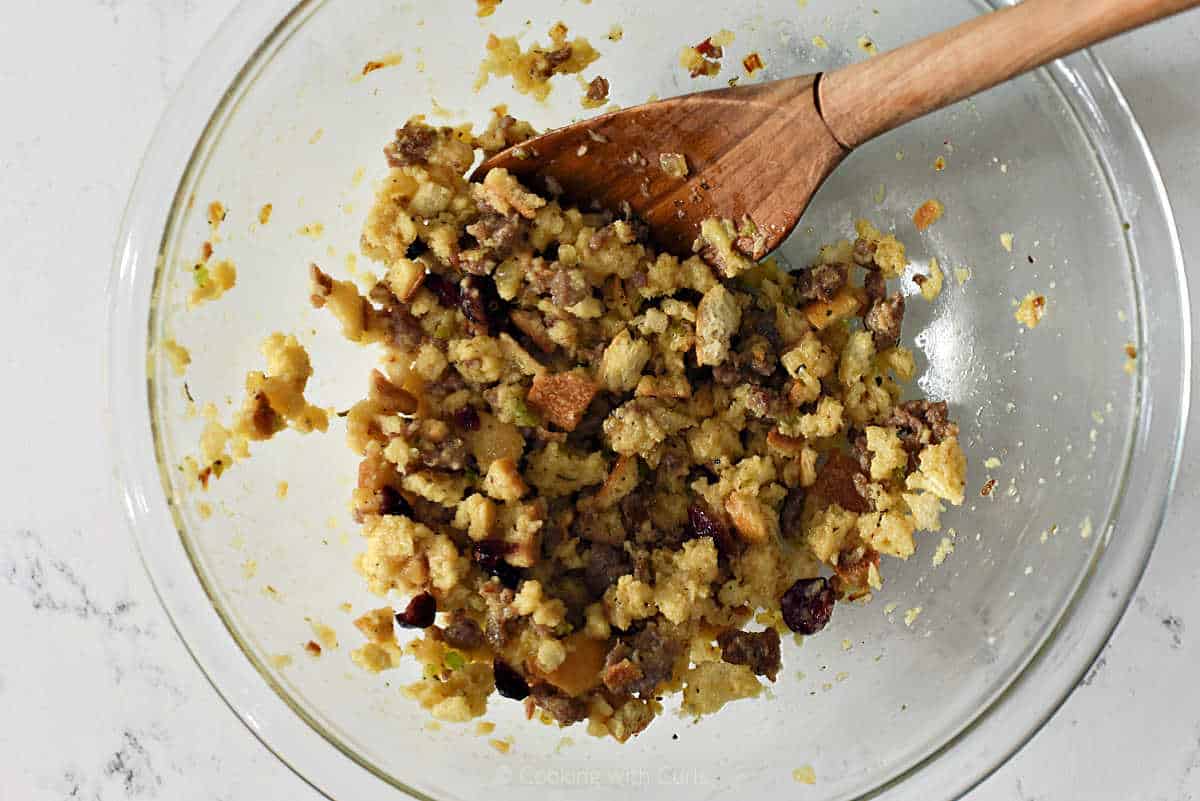 Stuffing ingredients mixed together in a bowl with a wooden spoon.