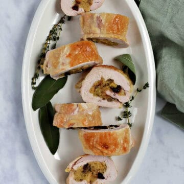 Stuffed turkey breast in seven slices on a serving platter.