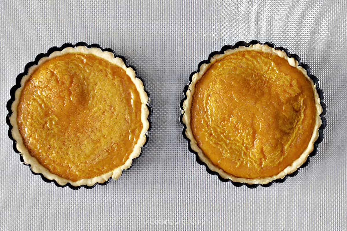 Two baked mini pumpkin pies.