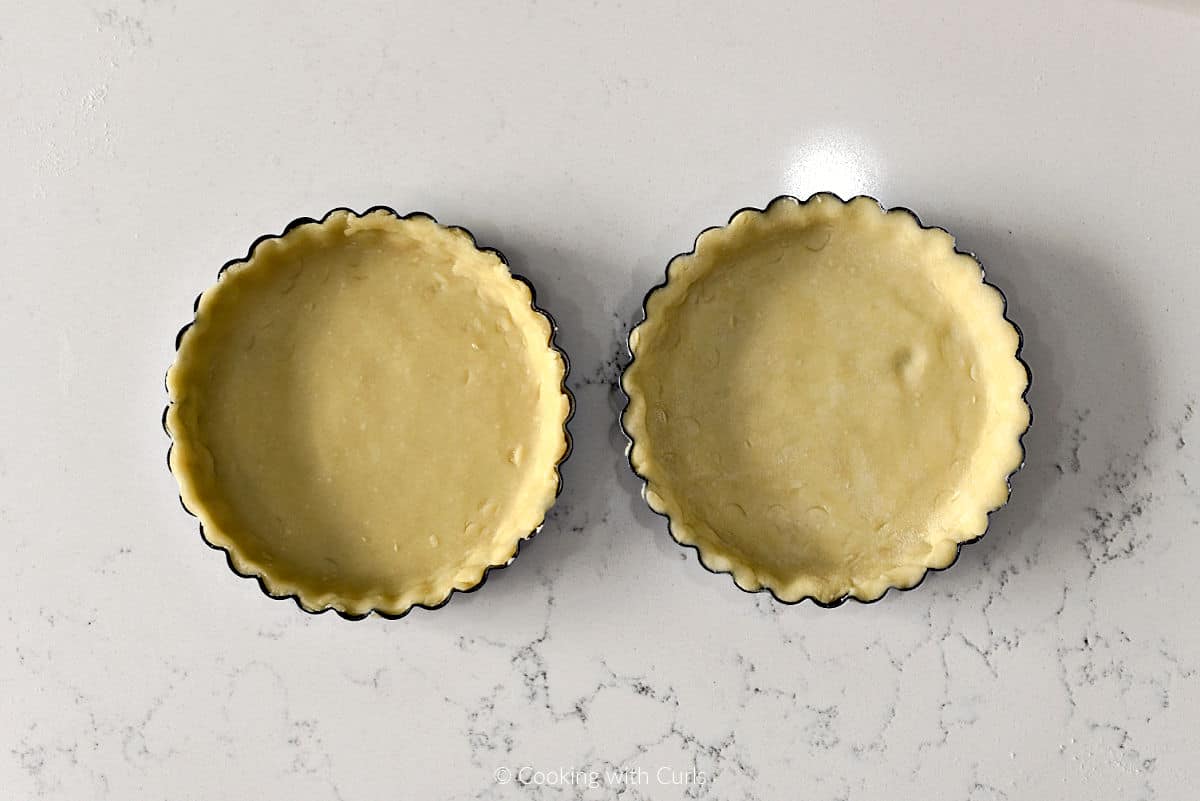 Two mini pie crusts in tart pans.