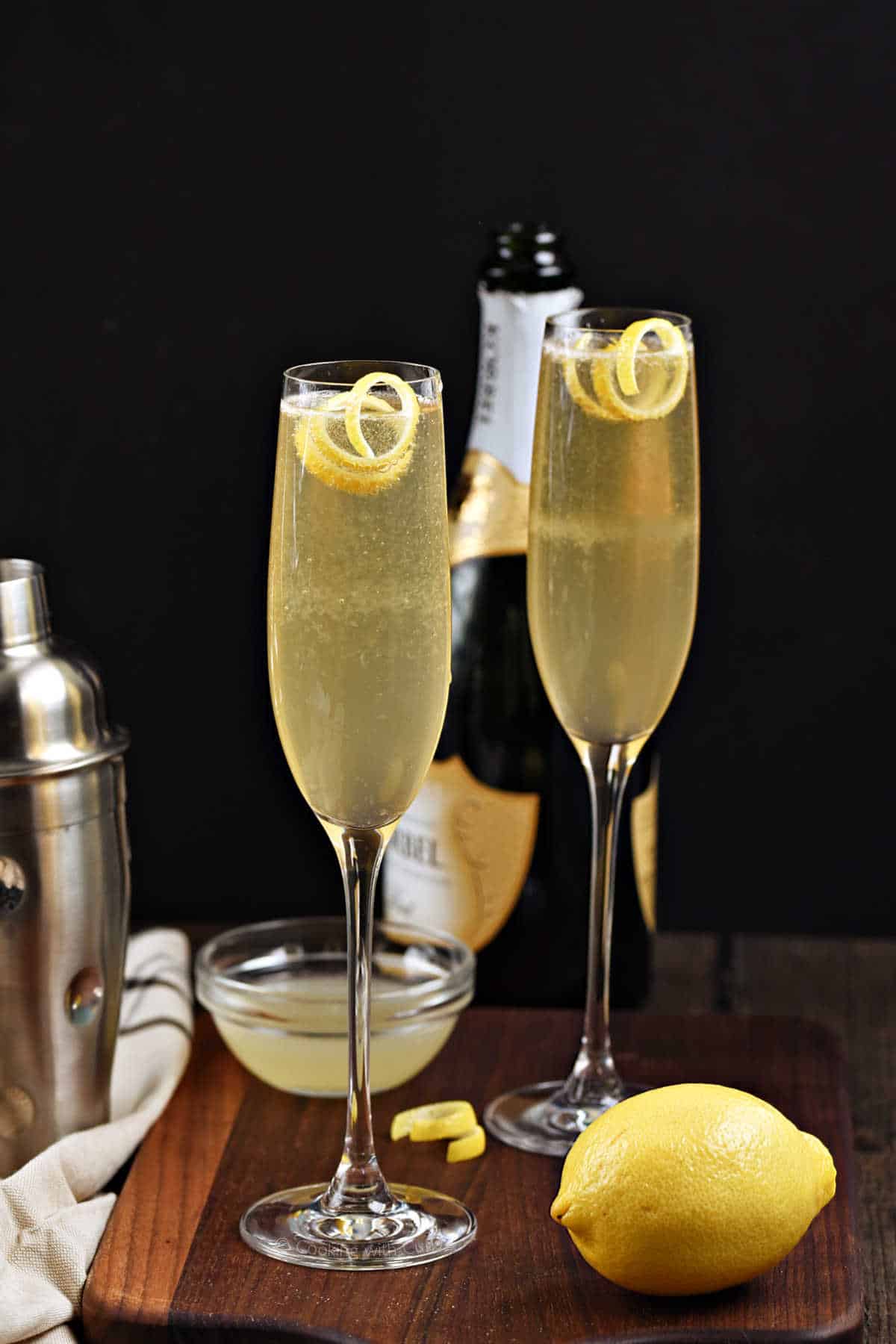 Yellow French 75 Cocktail in champagne flutes with lemon twist.