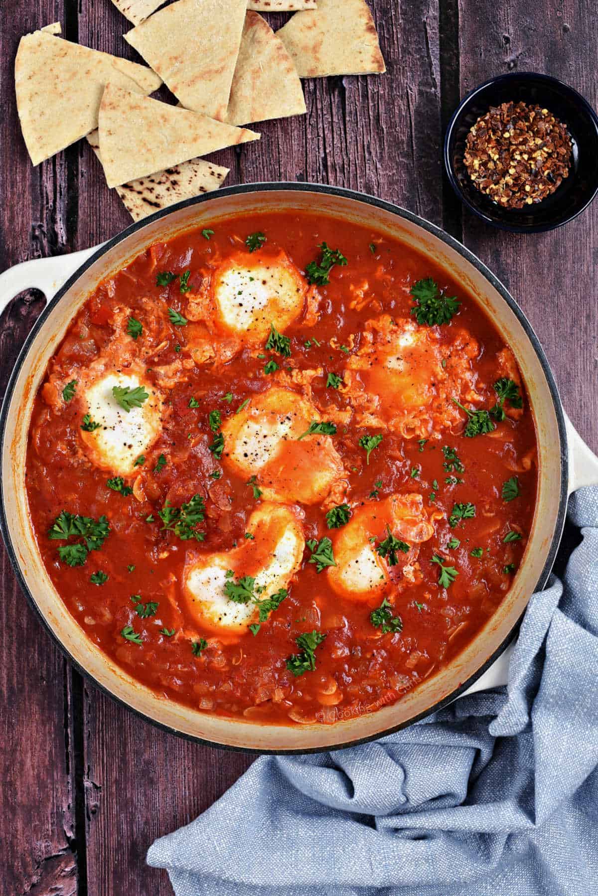 Six eggs in tomato sauce cooked in a skillet.