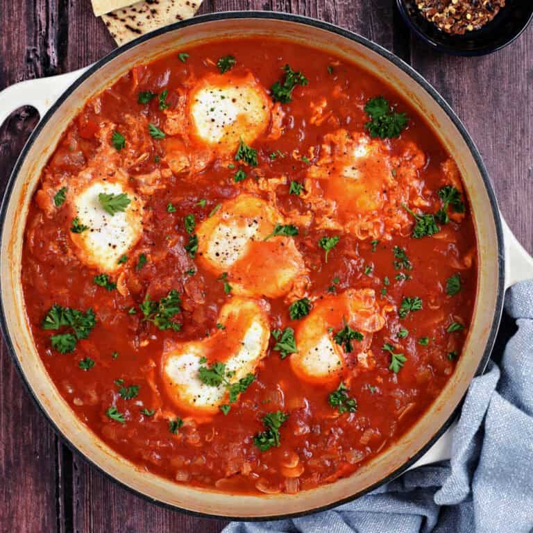 Six eggs in tomato sauce cooked in a skillet.