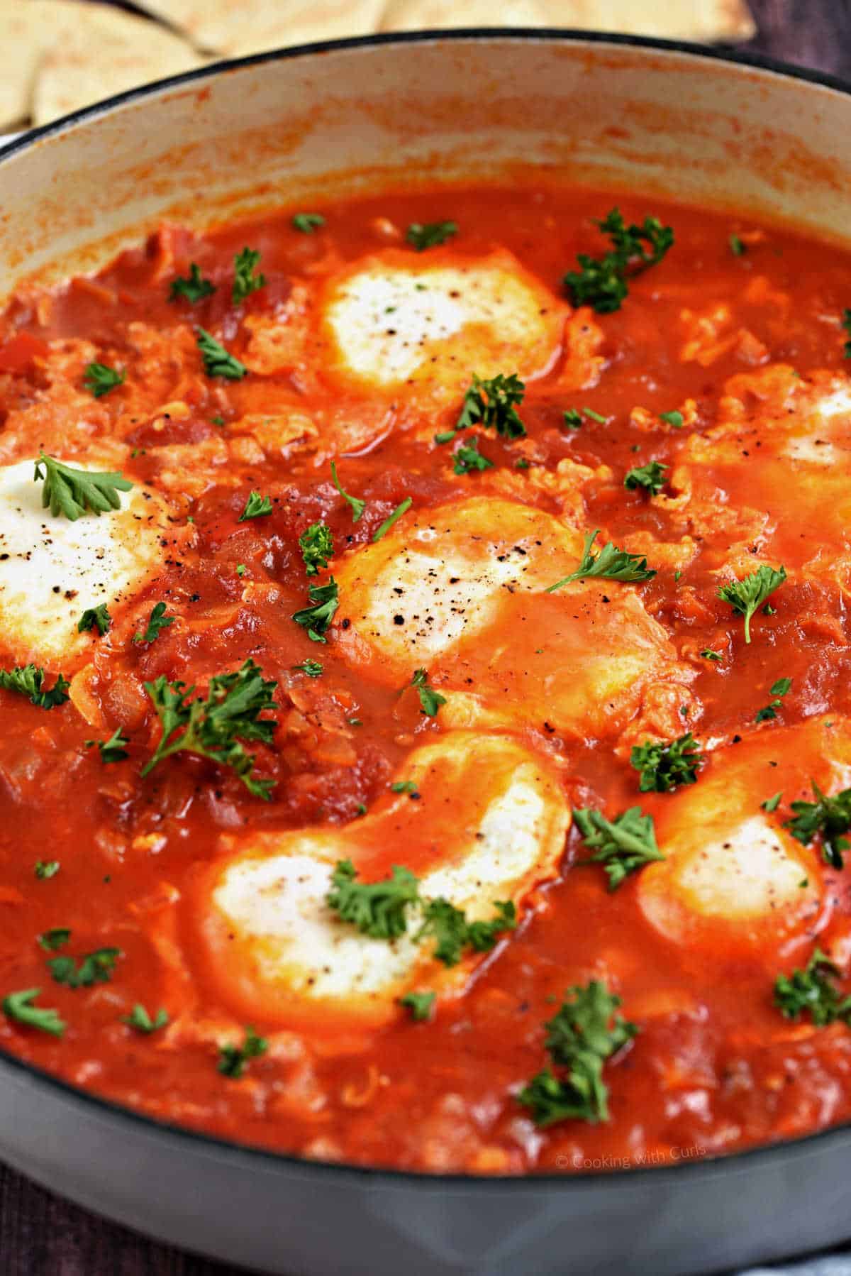 Poached eggs in tomato sauce sprinkled with parsley.